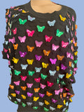 Black sweater with colorful butterfly patterns on a neutral background