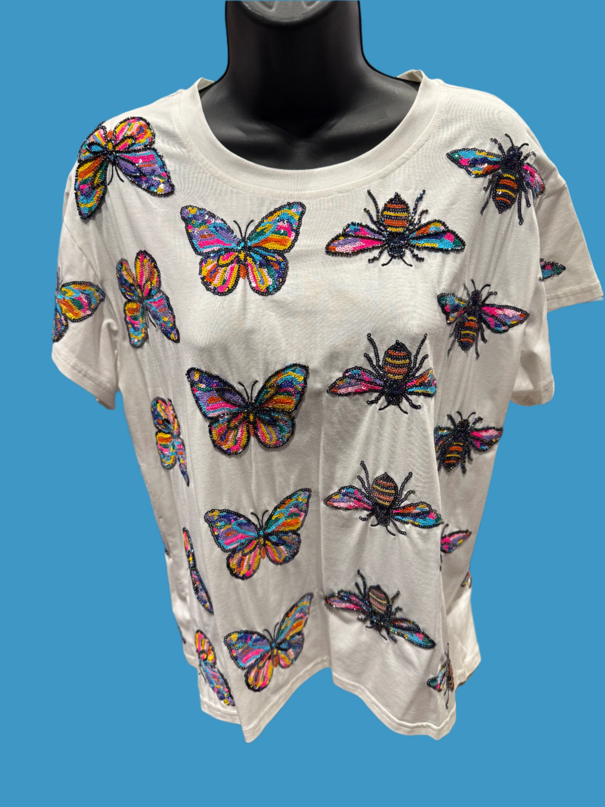 White t-shirt with colorful butterfly and bee patterns on a mannequin.