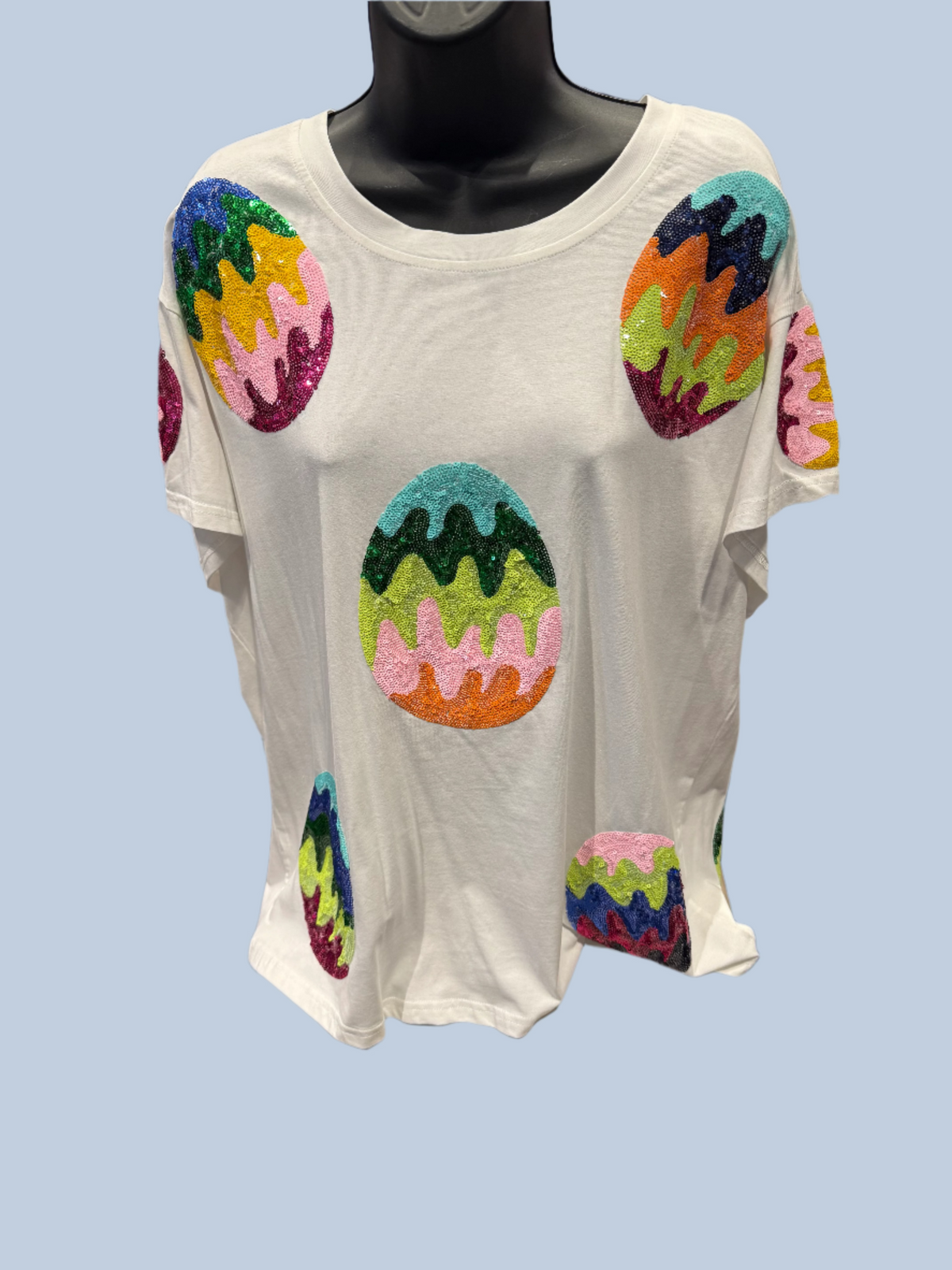 White t-shirt with colorful abstract designs on a mannequin in a store setting.