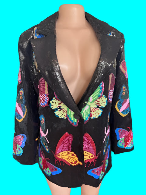 Mannequin wearing a black sequined jacket with colorful butterfly patterns on a dark background.