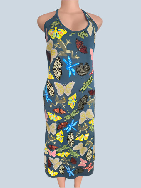 Person wearing a sleeveless dress with colorful butterfly pattern in front of a fireplace.